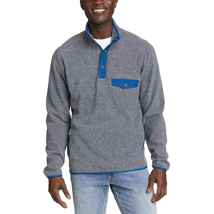 A man wears a heathered gray mock neck fleece with a blue snap pocket on the chest and blue trim details on the cuffs and hem.