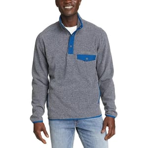 A man wears a heathered gray mock neck fleece with a blue snap pocket on the chest and blue trim details on the cuffs and hem.