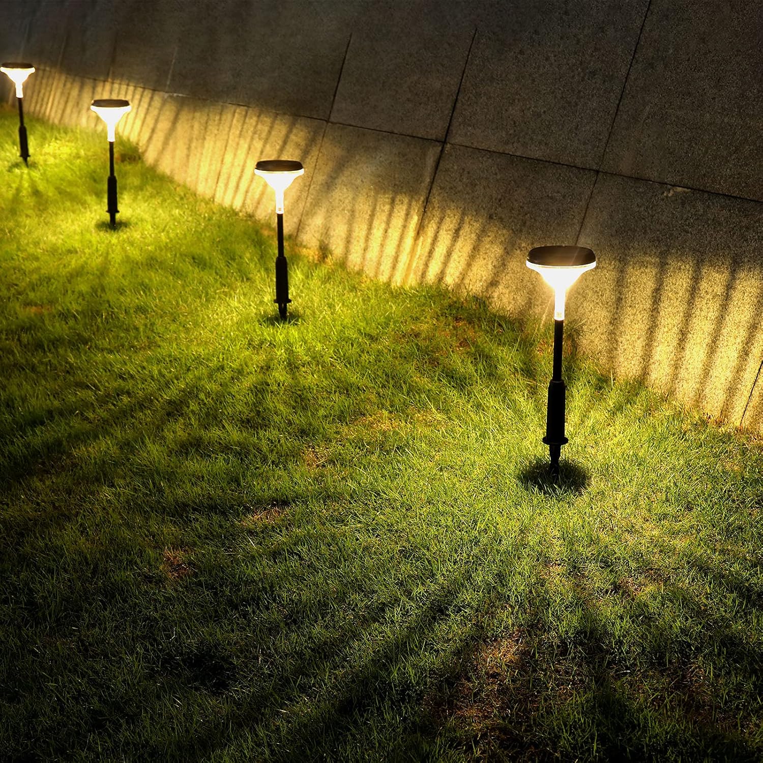 Outdoor solar-powered garden lights casting light on the grass at night.