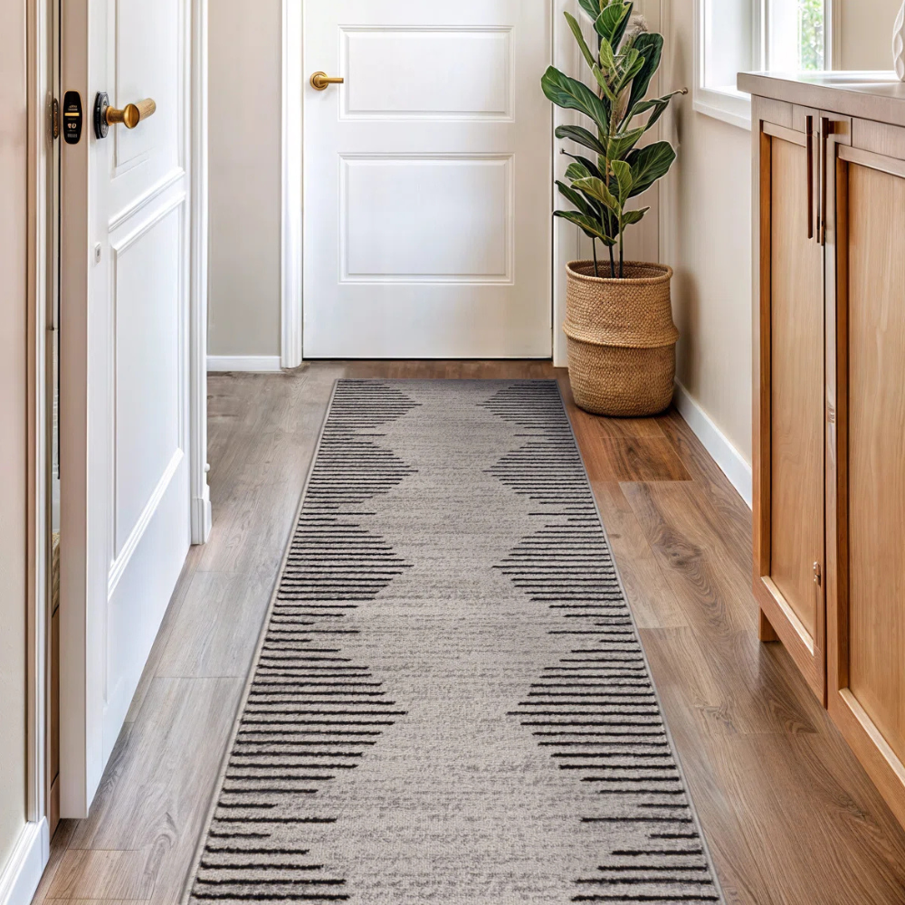 Hallway with a geometric-patterned runner rug and a potted plant in a woven basket beside a white door.