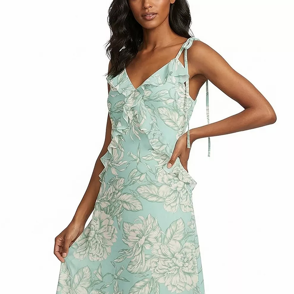 A woman is wearing a light turquoise floral dress with ruffled details on the bodice and tie straps.