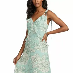 A woman is wearing a light turquoise floral dress with ruffled details on the bodice and tie straps.