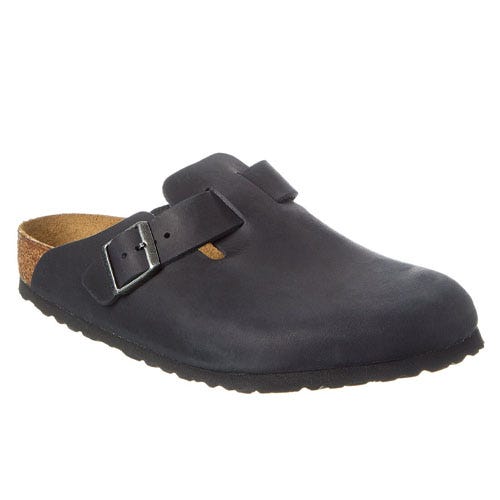 A dark-colored slip-on shoe with a cork footbed and an adjustable buckle strap across the top.