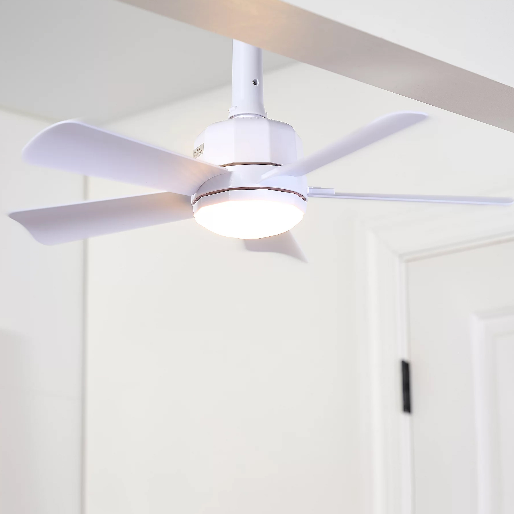 A white ceiling fan with a built-in light fixture mounted on the ceiling. The fan has five blades.