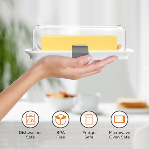 A hand holds a butter dish with a clear lid, showcasing a stick of butter. Icons indicate it is dishwasher safe, BPA free, fridge safe, and microwave oven safe.