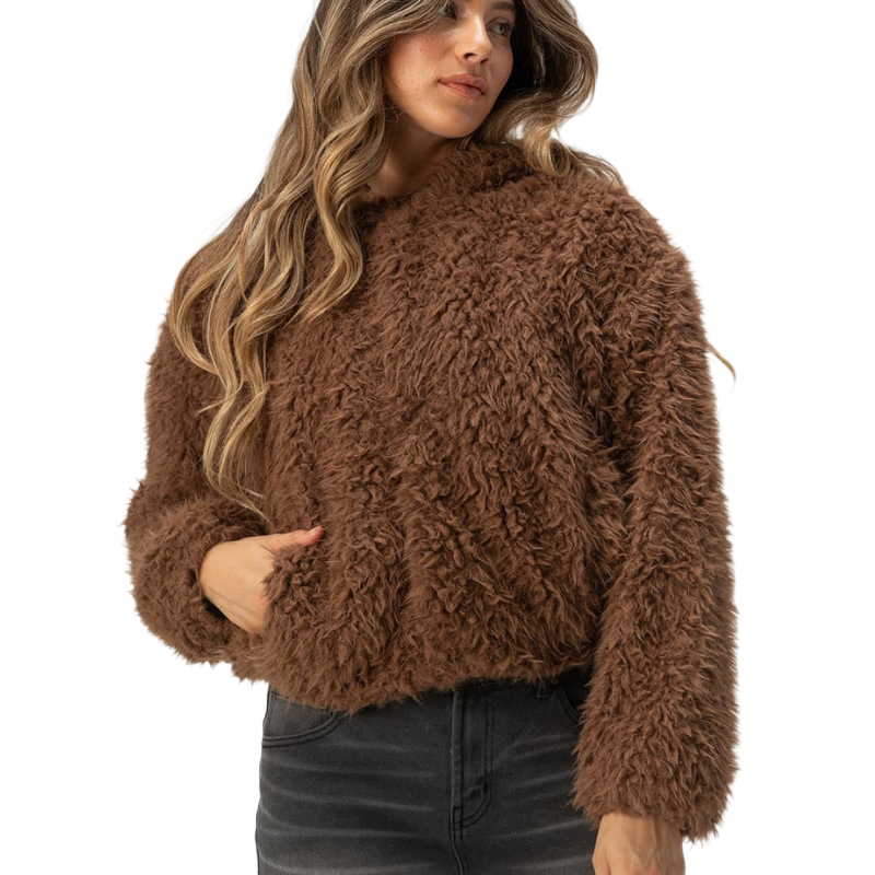 Brown fur hooded jacket with a plush, textured appearance, featuring a loose fit and long sleeves. The model is wearing it with dark jeans.