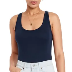 A woman is wearing a navy blue tank top and light blue jeans, complemented by a gold necklace with a rectangular pendant.