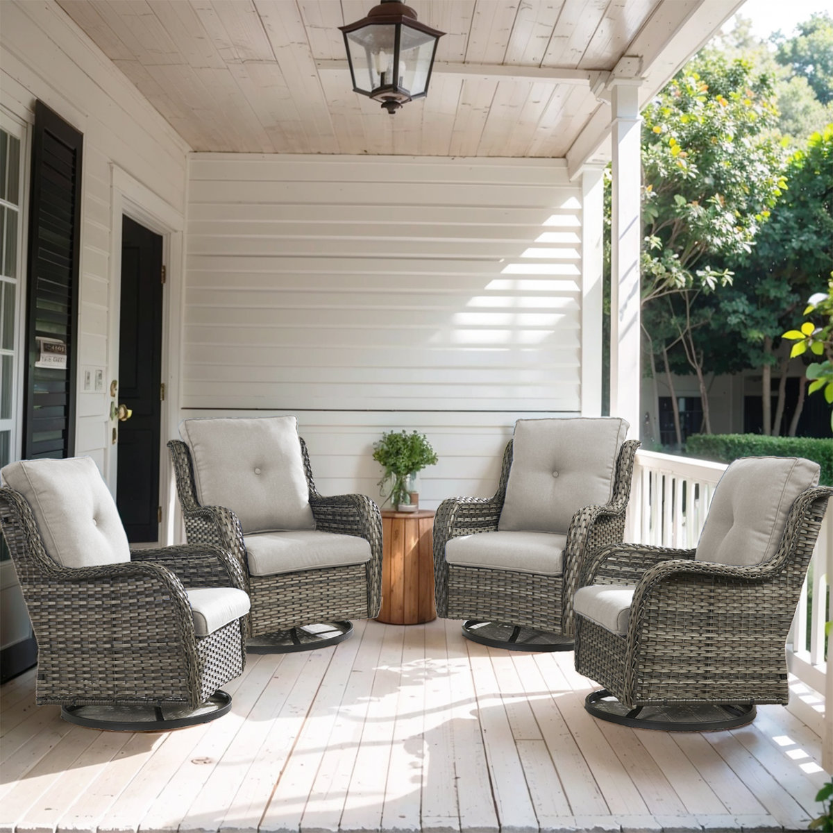 Four cushioned wicker swivel chairs are arranged on a covered porch, surrounding a small wooden side table.
