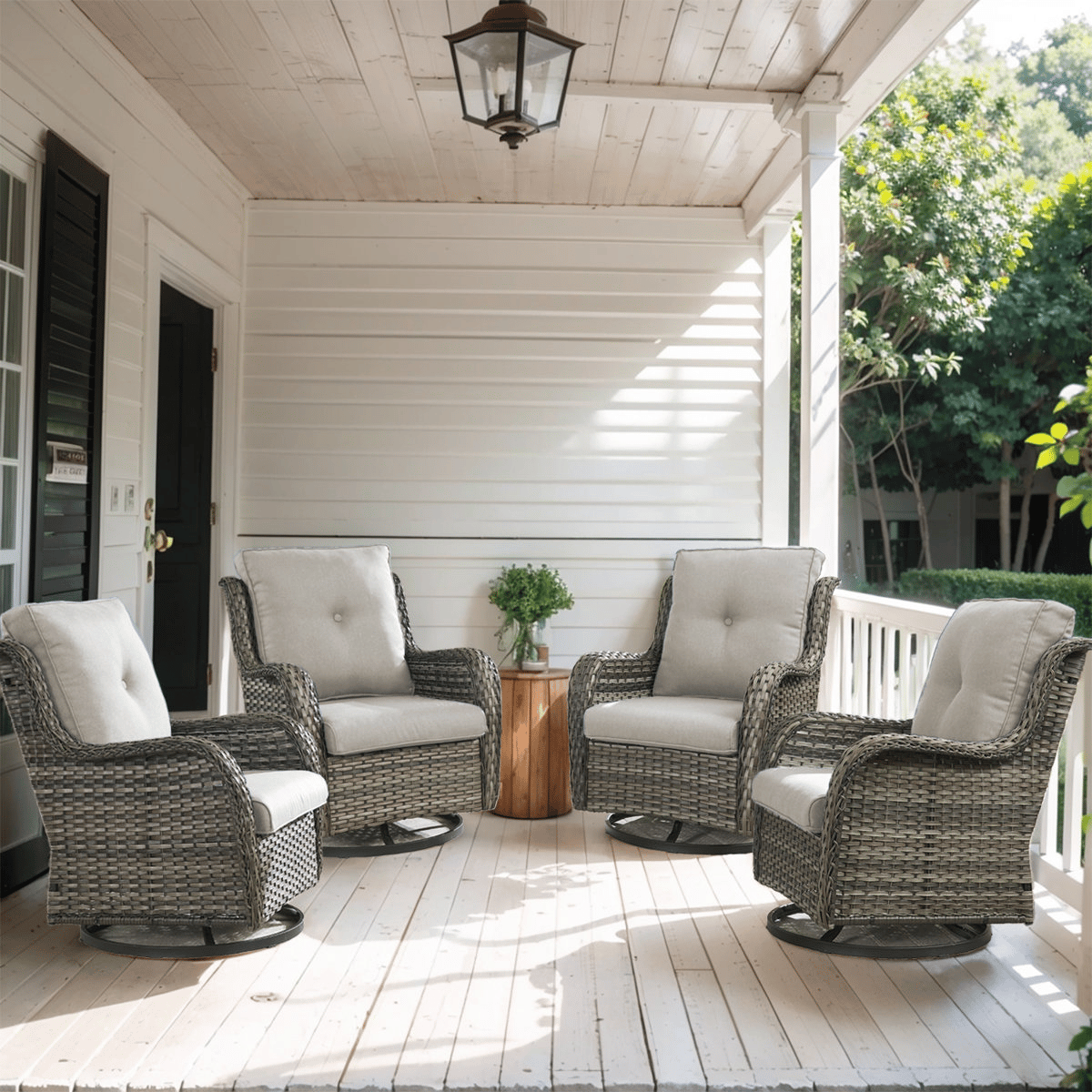 Four cushioned wicker swivel chairs are arranged on a covered porch, surrounding a small wooden side table.