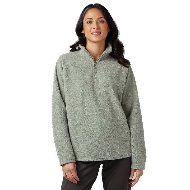 A woman is wearing a light green, half-zip sherpa top with a high collar and long sleeves.