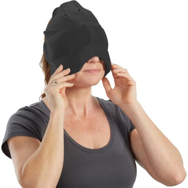 A woman wears a black cooling headache cap covering her eyes and head. The cap is designed to relieve headaches and migraines by providing cold therapy, contouring to the shape of the head for comfort.