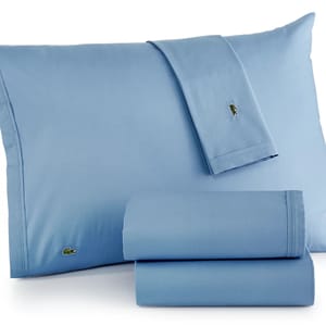 Blue Lacoste cotton percale sheet set featuring an embroidered crocodile logo, includes a flat sheet, fitted sheet, and pillowcases.