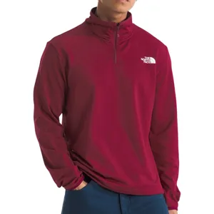 A male model is wearing a maroon The North Face quarter-zip pullover paired with blue pants.