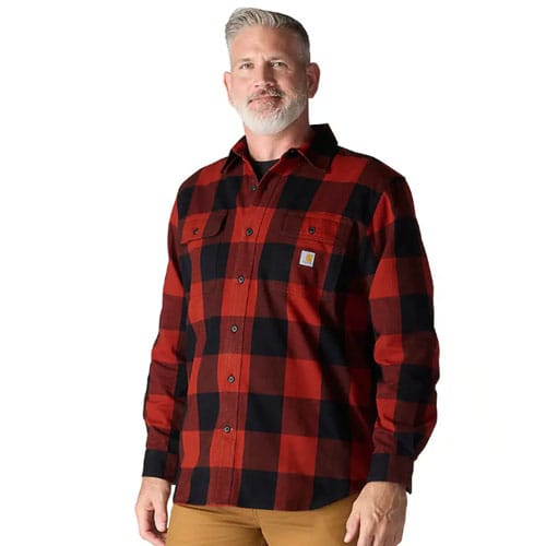 A man wearing a red and black plaid long-sleeve shirt with button-down pockets and brown pants.