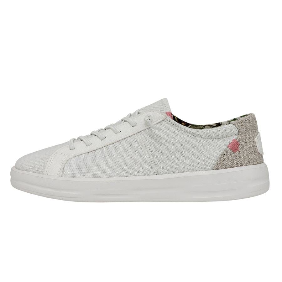 A white low-top sneaker with subtle pink and gray accents, featuring a simple lace-up design and a plush lining with patterned details on the interior.