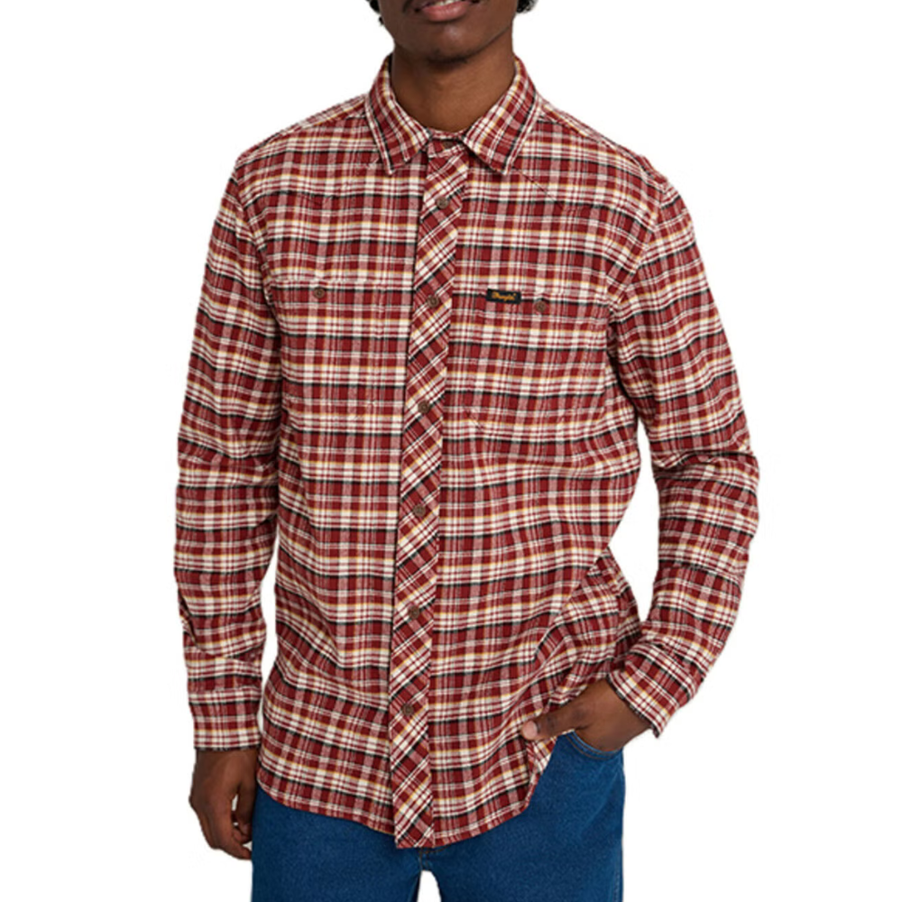 A man is wearing a red and white plaid long-sleeve shirt with a folded collar, paired with blue pants.