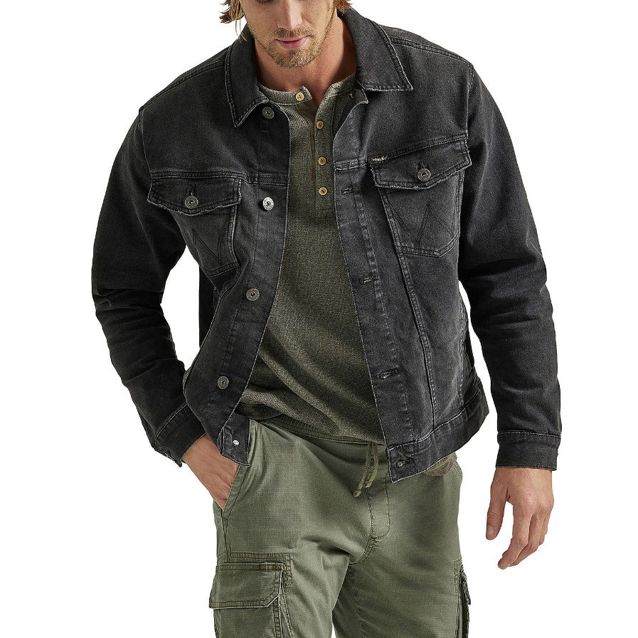 A man wearing a black denim jacket over a green henley shirt with olive cargo pants.