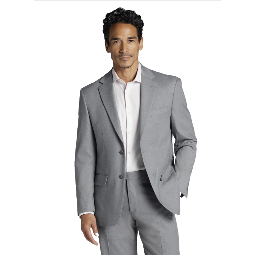 A man models a light gray suit from Men's Wearhouse featuring a two-button jacket with notched lapels and matching trousers, paired with a white dress shirt.