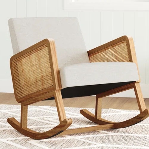 A rocking chair with a wooden frame, featuring rattan armrests and a cushioned seat and backrest in light upholstery, resting on curved wooden rockers.