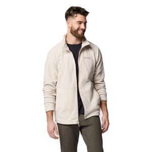 A man is wearing a light-colored Columbia fleece jacket with a high collar, along with a dark shirt and khaki pants.