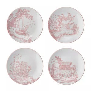 Set of four decorative plates featuring red toile-style designs with pastoral scenes, including children playing, a doghouse, and a person picking flowers.