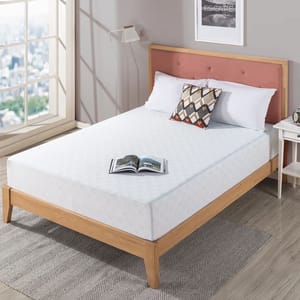 10\“ Queen Memory Foam Mattress on a wooden bed frame with a light pattern, accompanied by white pillows and a decorative cushion, beside a small white nightstand with a lamp in a bright room with large windows.