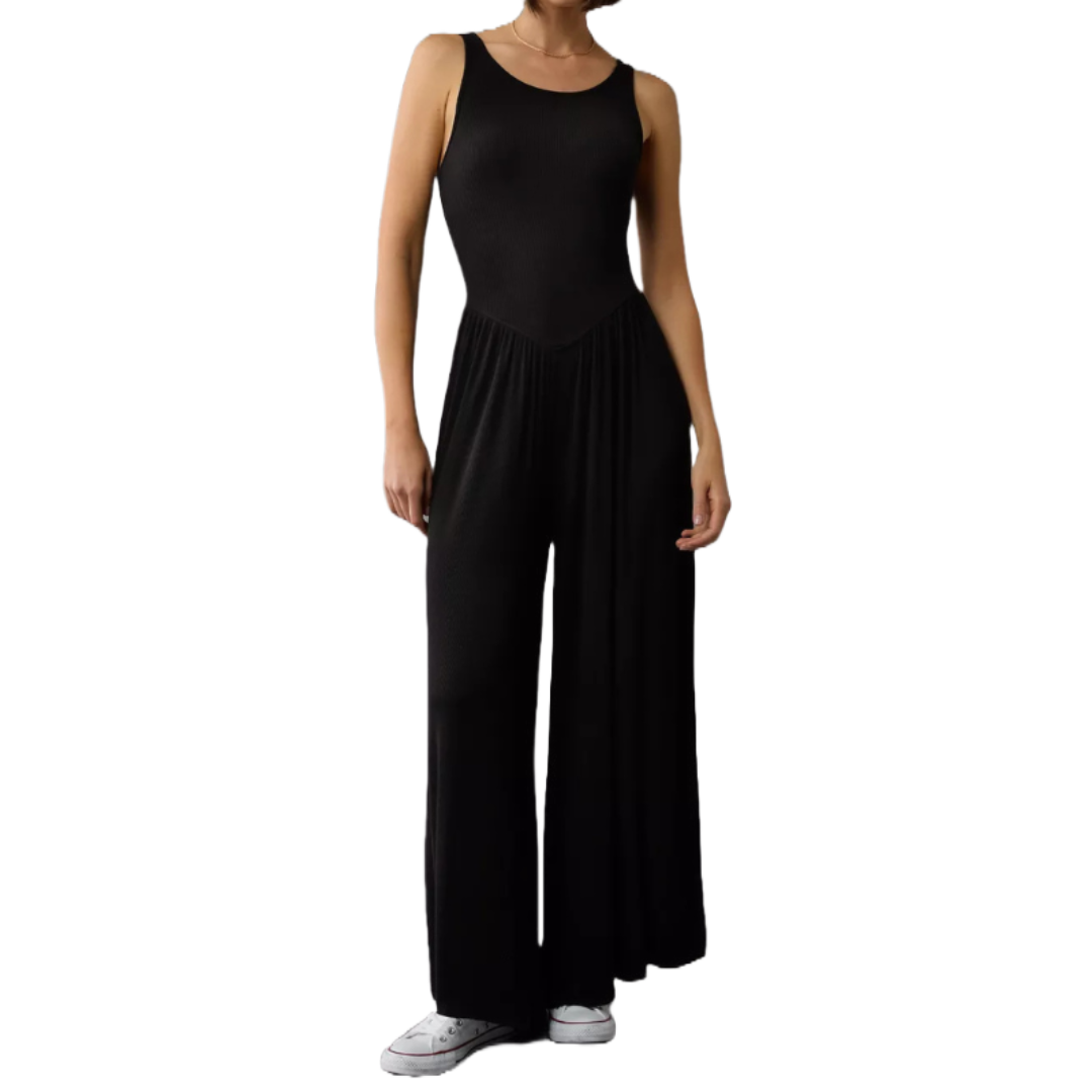 A black high neck jumpsuit featuring a sleeveless design with wide-legged pants and a fitted bodice, paired with white sneakers.