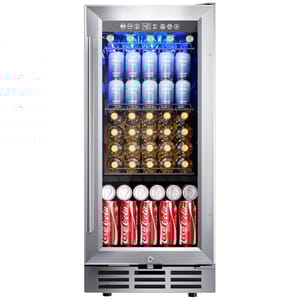A stainless steel mini fridge with a glass door displaying neatly stacked drinks: top shelf has blue cans, the middle shelf holds glass bottles with yellow caps, and the bottom shelf contains red Coca-Cola cans.