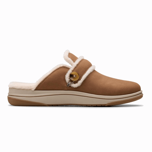 Clarks Cozy Cloudstepper Slippers are tan slip-ons with a fluffy lining, featuring a button detail and a cushioned sole for comfort and support.
