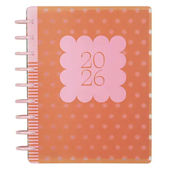 An orange 2026 planner with a pink square design on the cover, featuring small polka dots and a spiral binding on the left side.