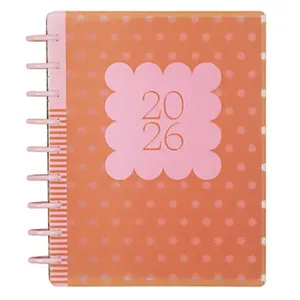 An orange 2026 planner with a pink square design on the cover, featuring small polka dots and a spiral binding on the left side.