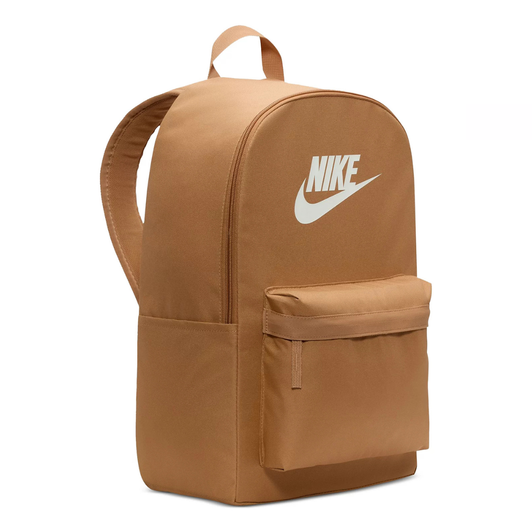 A brown Nike Heritage Backpack featuring the Nike logo in white. It has a large main compartment and a smaller front pocket, with padded shoulder straps and a top handle for easy carrying.