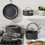 A set of non-stick cookware, including a frying pan, saucepans, and a stockpot, with glass lids and stainless steel handles, is displayed on a kitchen stove and shelves against a tiled backsplash.