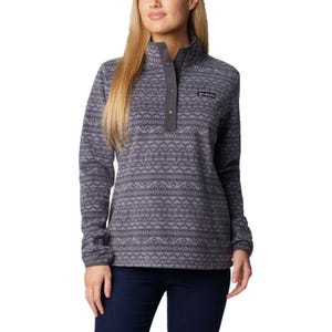 A woman wears a gray patterned Columbia fleece pullover with a snap placket and long sleeves, paired with dark jeans.