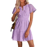 A woman is wearing a short-sleeve lavender eyelet mini dress with a cinched waist, V-neck, and flared hem, paired with a brown crossbody bag.
