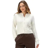 A woman wearing a white cable-knit cardigan and brown pants.