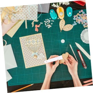 A One-Year Craftsy Membership provides access to a variety of crafting classes and projects, including scrapbooking and cardmaking, along with tools like paper punches, craft knives, and embellishments such as buttons and ribbons for creative projects.