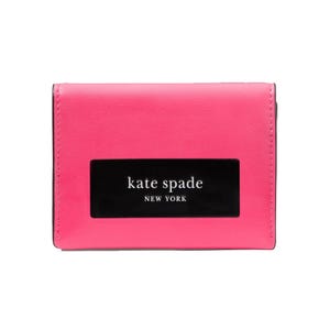 A pink Kate Spade New York wallet with a black rectangular logo on the front.