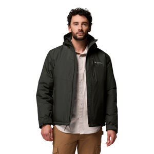 A man wears a dark green Columbia jacket over a light shirt and tan cargo pants.