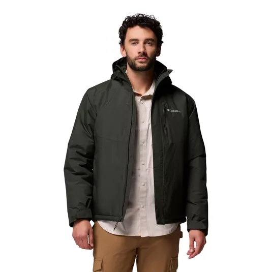 A man wears a dark green Columbia jacket over a light shirt and tan cargo pants.