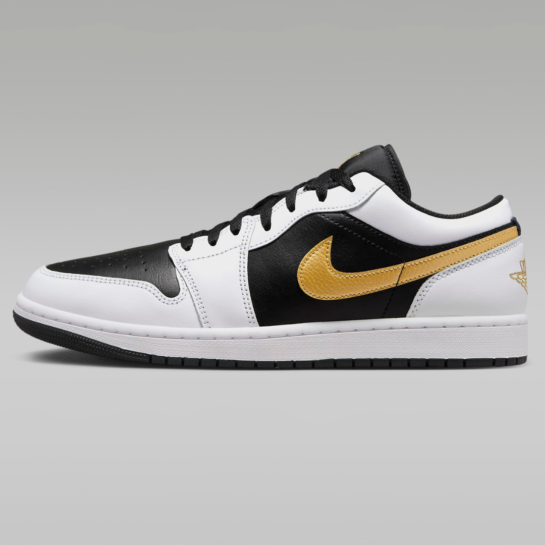 A pair of Air Jordan 1 Low sneakers featuring a black and white color scheme with a metallic gold Nike Swoosh and the Jumpman logo on the heel.