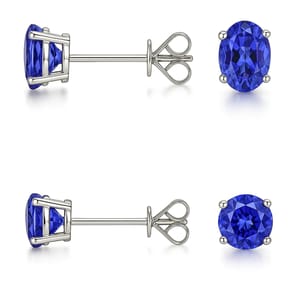 Two pairs of stud earrings featuring blue gemstones in silver settings; one oval-shaped and the other round.