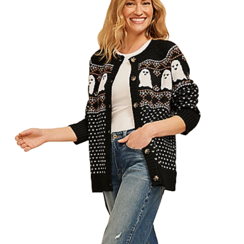 A woman wears a black cardigan featuring white ghost patterns and decorative buttons, paired with a white top and blue jeans.