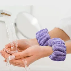 A person wearing purple microfiber wristbands is using a tap to wash their hands.