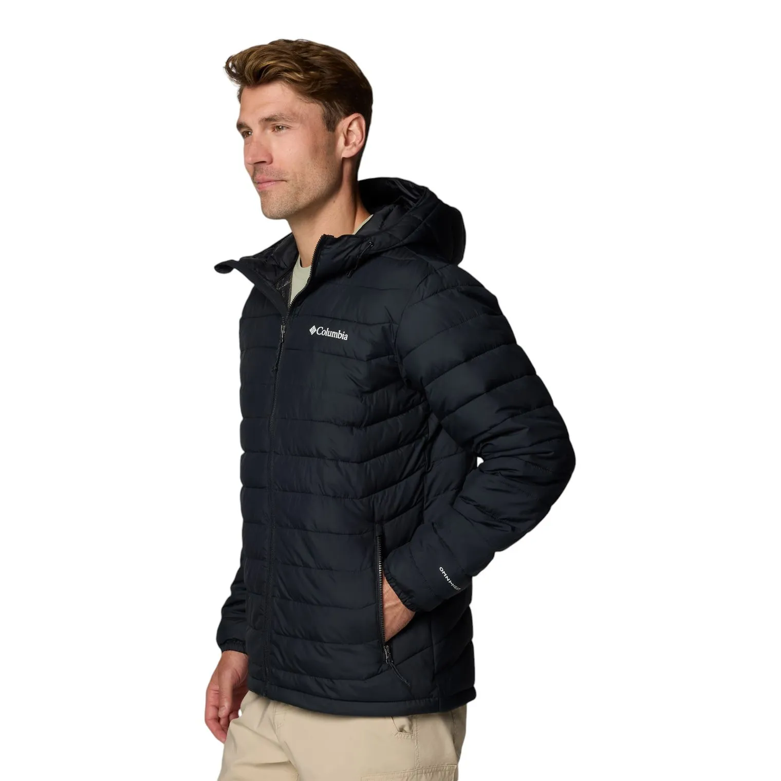 A man is wearing a black Columbia puffer jacket with a hood, featuring a front zipper and brand logos. He has his hand in the pocket, and the jacket appears suitable for cold weather.