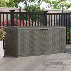 Outdoor storage box with a woven design, set on a patio with flowers and a fence in the background.