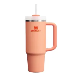 A peach-colored Stanley insulated tumbler with a handle and lid featuring a built-in straw.