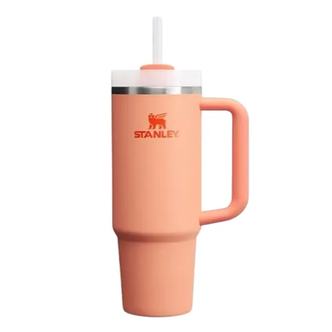 A peach-colored Stanley insulated tumbler with a handle and lid featuring a built-in straw.