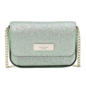 A green glitter crossbody bag with a gold chain strap and a \“Kate Spade New York\“ logo plaque on the front flap.