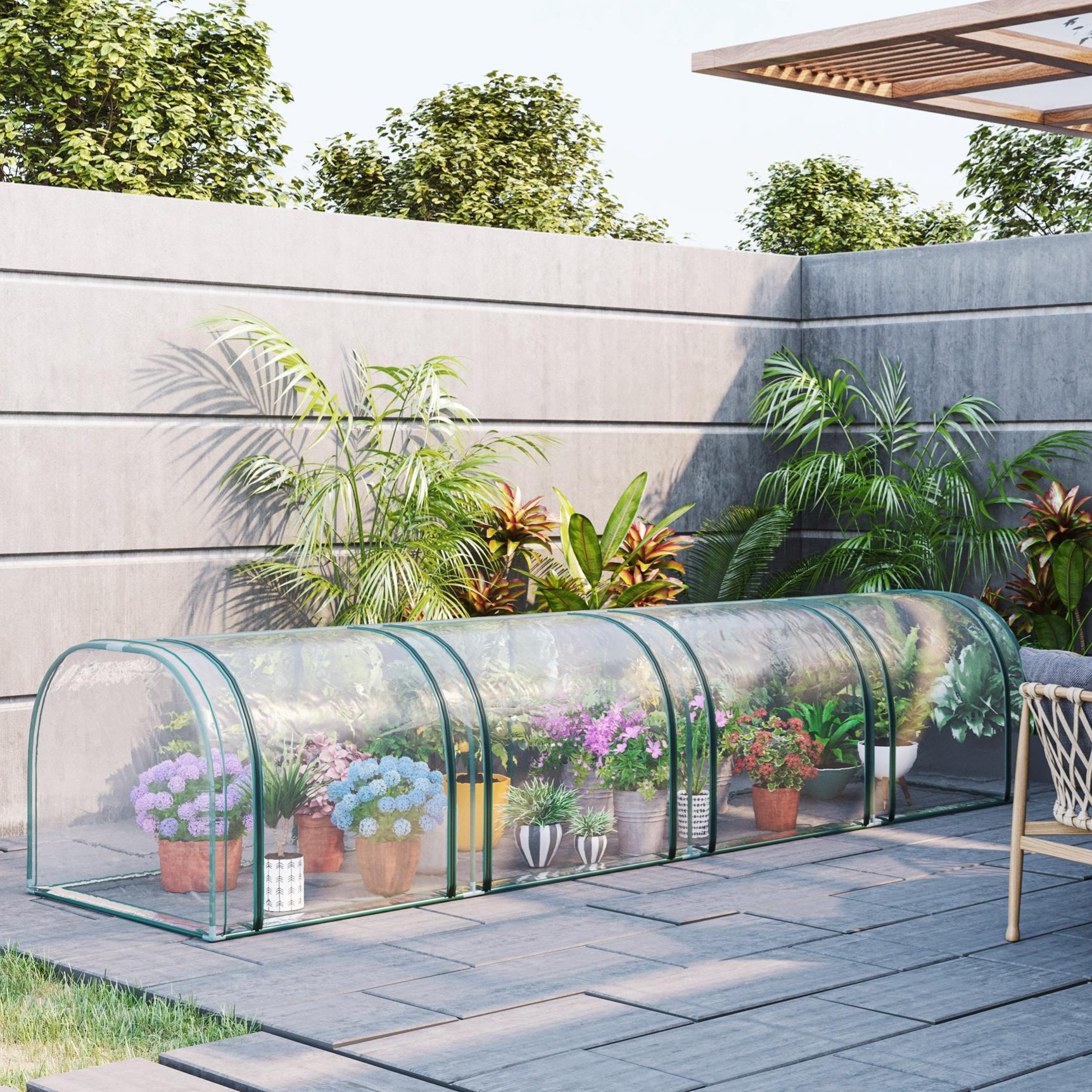 A transparent greenhouse tunnel with various potted plants and flowers is shown on a modern patio, surrounded by lush greenery and a concrete wall.